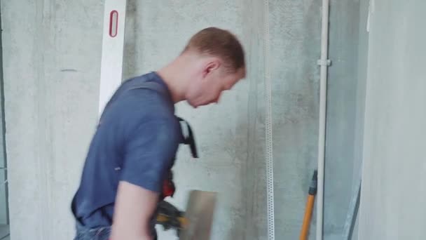 Man arbetare gör reparationer i lägenheten genom att sätta spackel på väggarna. Byggverksamhet. — Stockvideo