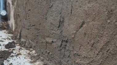 Erkekler duvar yalıtımı ve ev temeline mala sıva yapıyor. Kendin yap.