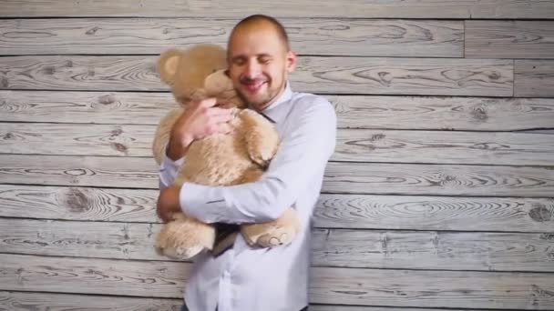 Мужчина держит плюшевого мишку. Бизнесмен обнимает игрушечного медведя — стоковое видео