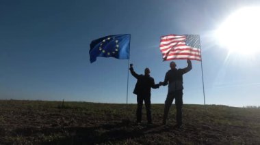 Uluslararası ilişkiler, ABD ve Avrupa Birliği 'nin uluslararası ortaklığı kavramı. Amerikan ve Avrupa bayrağının arka planında iki adamın silueti.