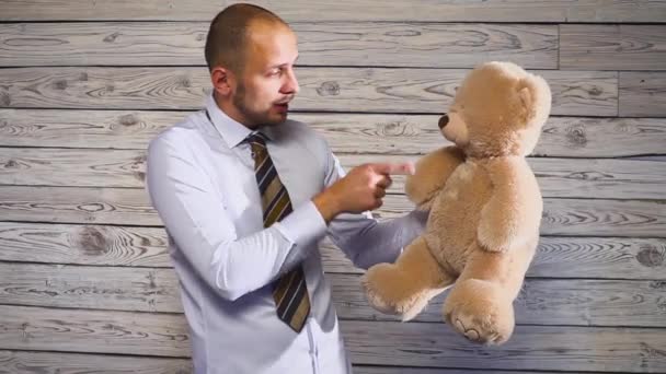 Young angry businessman beating a stuffed bear toy in his office. Concert on the theme of frustration — Stock Video