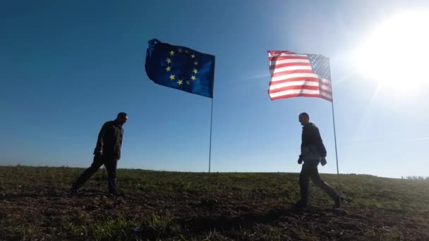 Koncepce mezinárodních vztahů, mezinárodního partnerství USA a Evropské unie. Silueta dvou mužů na pozadí americké a evropské vlajky.