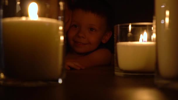 Padre besando hijo cerca de velas encendidas en la oscuridad. Familia feliz celebrando cumpleaños de los niños — Vídeo de stock