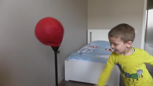 Jongen boksen in kamer met speelgoed boksen peer en handschoenen — Stockvideo