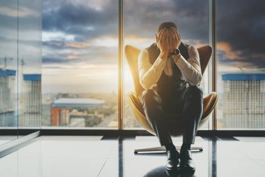Kederli bir girişimci işinin iflasını yaşıyor; kederli bir işadamı ellerini pencerenin yanındaki bir koltuğa koyup yüzünü kapatıyor arkasında fırtınalı bir gökyüzü var.