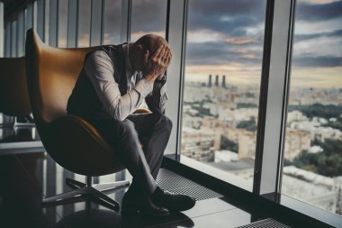 Yorgun ve çökmüş bir girişimci, lüks bir ofis gökdeleninin yanındaki koltukta otururken, ortaklık şirketinin krizi ve iflası hakkında endişeleniyor.