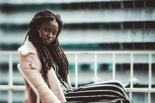 一个真正的倾斜移位肖像 有选择性的聚焦在一个耀眼的年轻黑人女人的脸和头发上 一个可怕的锁坐在阳台上 右边有一个复制的空间 — 图库照片