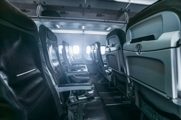 暗い航空機のインテリア 脇の下と現代の空の薄い革の座席の行は フィールドの浅い深さは 前景に選択的な焦点は 荷物棚を開いた — ストック写真