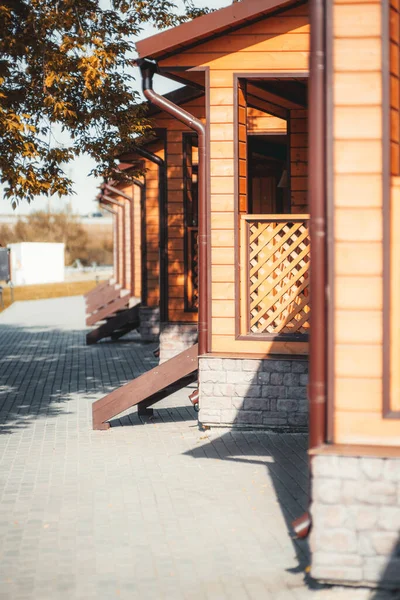 Solda ağaçlarla dolu bir sokak ve verandalarda eşit ahşap verandalar, bir kamp alanının kulübeleri ya da bir gençlik yurdu, güneşli bir gün, ön planda seçici bir odak ile