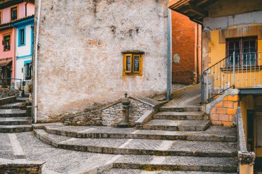 Cudillero 'da dokulu duvarlar, taş basamaklar, küçük bir çeşme ve canlı pencere çerçeveleri, büyüleyici Akdeniz köyü mimarisi ve katmanlı yollar yakalayan renkli kırsal bir sokak.