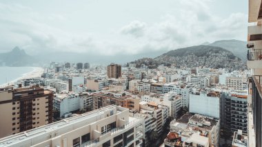Brezilya, Rio de Janeiro, Ipanema ve Arpoador üzerinde geniş açı manzarası, yoğun sahil binalarını, Atlantik Okyanusu kıyılarını ve bulutların altındaki yeşil dağları gösteriyor.