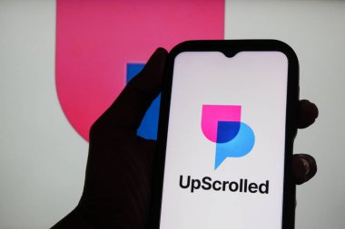 Bandung, Endonezya - 3 Şubat 2026: Bu fotoğraf ilüstrasyonlarında, UpScrolled uygulamasının logosu arka planda TikTok 'un görünür olduğu bir cep telefonunda sergilenmektedir.
