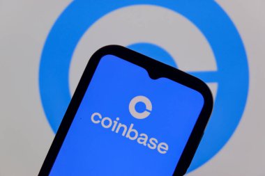 Bandung, Endonezya - 13 Şubat 2026: Bu fotoğraf ilüstrasyonlarında, Coinbase logosu bir cep telefonunda sergileniyor ve şirket markası arka planda görünüyor.
