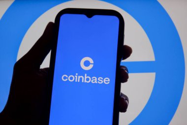Bandung, Endonezya - 13 Şubat 2026: Bu fotoğraf ilüstrasyonlarında, Coinbase logosu bir cep telefonunda sergileniyor ve şirket markası arka planda görünüyor.
