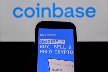 Bandung, Endonezya - 13 Şubat 2026: Bu fotoğraf ilüstrasyonlarında, Coinbase logosu bir cep telefonunda sergileniyor ve şirket markası arka planda görünüyor.