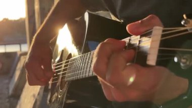 Adam açık havada gitar çalıyor. Yaz akşamı.