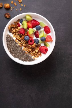 Kefir, chia, granola ve taze meyvelerle dolu bir kâsenin en üst görüntüsü. Temiz ve doğal bir şekilde dikey bir çerçeve. Uzayı kopyala Sağlıklı kahvaltı ve dikkatli yemek kavramı.