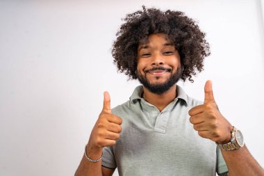 Mutlu siyah adam gülümsüyor, beyaz bir arka planda onayını veriyor.