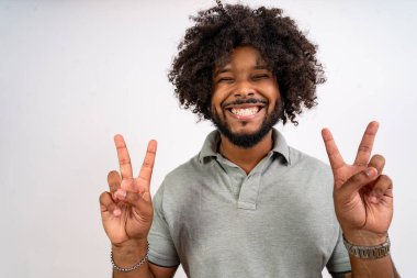 Mutlu genç adam barış işareti gösteriyor. İki eli kameraya gülümsüyor.
