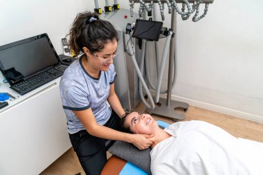 Klinikte bir kadının boynuna fiziksel terapi uygulayan fizyoterapist.