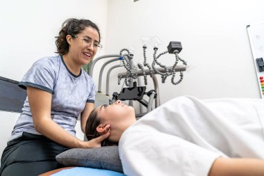 Klinikte genç bir kadın hastaya boyun masajı yapan kadın fizyoterapist.
