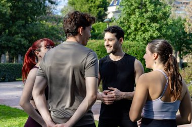 Arkadaşlar eğitimden sonra parkta konuşuyor ve gülümsüyor, sohbet ediyorlar.