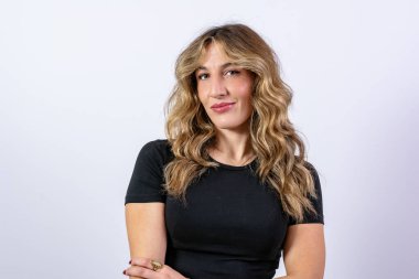 Genç bir kadın doğal olarak gülümsüyor ve temiz bir arkaplanda kameraya bakıyor.