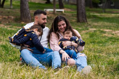 Mutlu bir aile çimenlerde oturur, dışarıda vakit geçirir ve çocukları dinlenir.