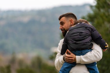 Omzunda çocuk taşıyan bir adam, dışarıda eğleniyor.