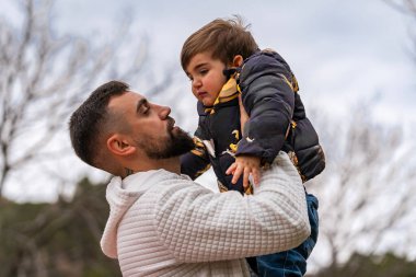 Mutlu baba küçük oğlunu tutuyor, sevgi ve sevgiyle birbirine bağlanıyor.