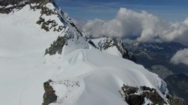 Gün ortasında karla kaplı dağ manzarası yukarıdan görülüyor