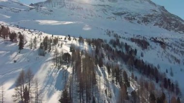 Kış manzarasında karla kaplı dağlar parlak güneş ışığı altında yükselir.