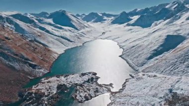 Karlı dağlardaki uzak bir buzul gölünün göz kamaştırıcı manzarası