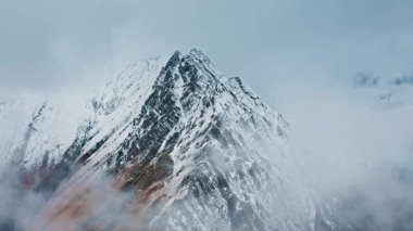 Sabah saatlerinde bulutlarla kaplı karlı dağ zirveleri