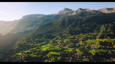 Bereketli yeşillik ve çiftliklerle gün batımında dağ vadisi manzarası