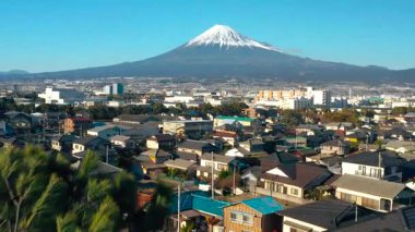 Fuji Dağı berrak mavi gökyüzünün altındaki canlı bir kasabaya bakıyor.