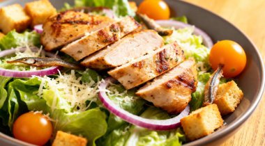 Kızarmış tavuk fileto ile Sezar salatası kırmızı soğan halkaları marul, kiraz, domates, kızarmış parmesan peyniri rendelenmiş ançüez.