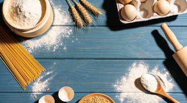 Mavi ahşap masa üzerinde buğday unuyla bezenmiş düz bileşim..