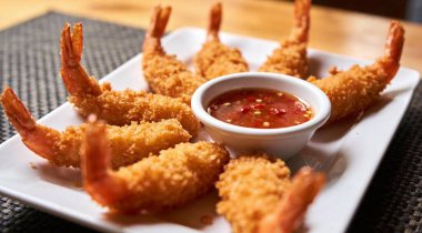 Kızarmış karides. Beyaz tabakta ekmek kırıntıları ve acılı tatlı soslu kızarmış karides..