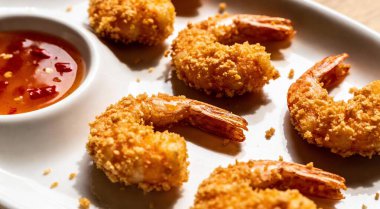 Kızarmış karides. Beyaz tabakta ekmek kırıntıları ve acılı tatlı soslu kızarmış karides..