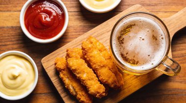 Bira, ketçap ve tahtanın üzerinde mayonez ile pişirilmiş tavuk şeritleri.