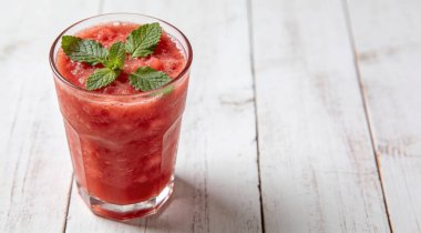 Beyaz ahşap arka planda taze nane yapraklı karpuz smoothie.