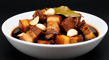 Filipinli Adobo Pork siyah arka planda beyaz bir kasede