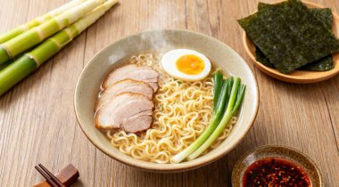 Tabakta lezzetli ramen ve ahşap masada malzemelerle bezenmiş düz bir kompozisyon. Erişte çorbası.