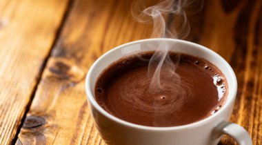 Tahta masada beyaz bir fincanda sıcak kalın çikolata.