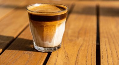 Tasty latte macchiato in glass on wooden table