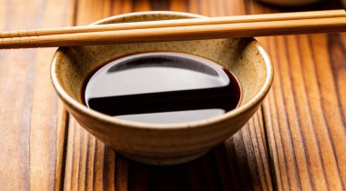 Soya soslu kase ve ahşap masada çubuklar, yakın plan.