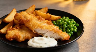 Lezzetli balık cipsi ve bezelye, yakın plan gri masada.