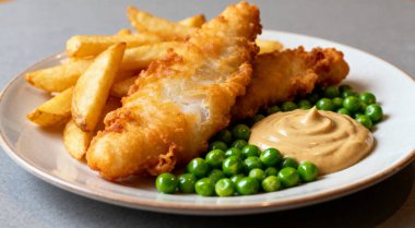 Lezzetli balık cipsi ve bezelye, yakın plan gri masada.