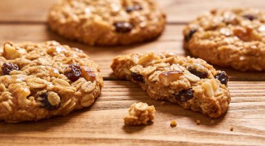 Kuru üzümlü ve fındıklı lezzetli yulaf ezmeli kurabiyeler ahşap masa üzerinde servis edilir.